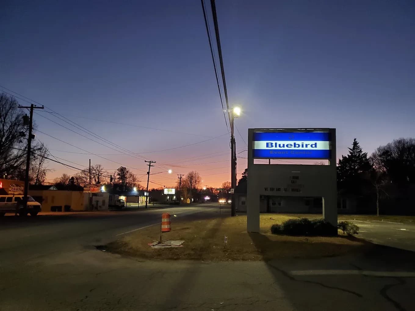 Illuminated Bluebird Event Center sign at dusk on Greensboro Road